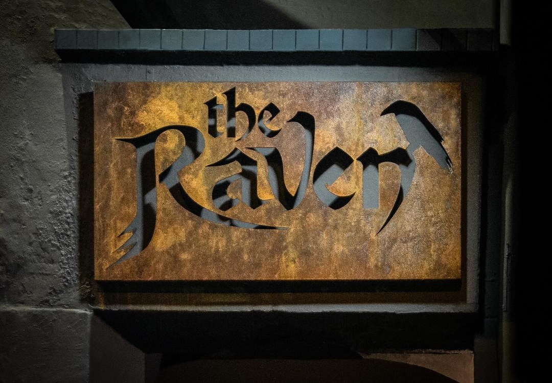 Placa de madeira entalhada com o nome the Raven.