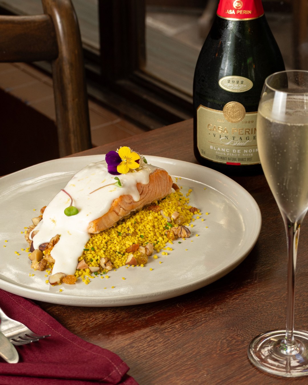Salmão grelhado coberto por molho bechamel cítrico, sobre couscous marroquino amarelo.